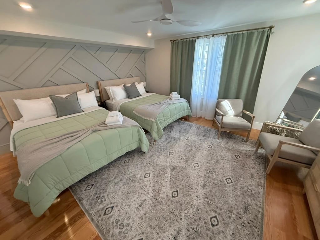 Same Airbnb bedroom after AMH turnover, both beds made with fresh linens, pillows and folded towels